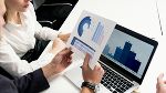 Mann und Frau analysieren Balken- und Tortendiagramm auf Blatt Papier vor einem Laptop am Tisch Mann und Frau analysieren Balken- und Tortendiagramm auf Blatt Papier vor einem Laptop am Tisch